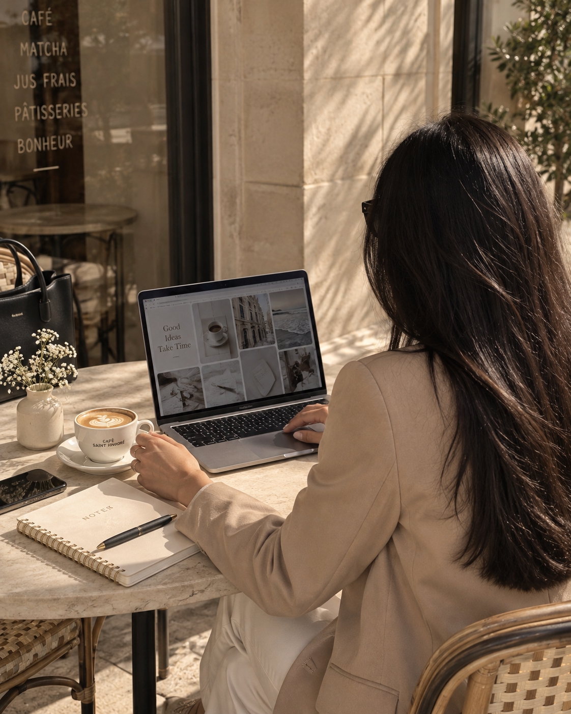 A creator planning content at a café with a laptop, notebook and coffee